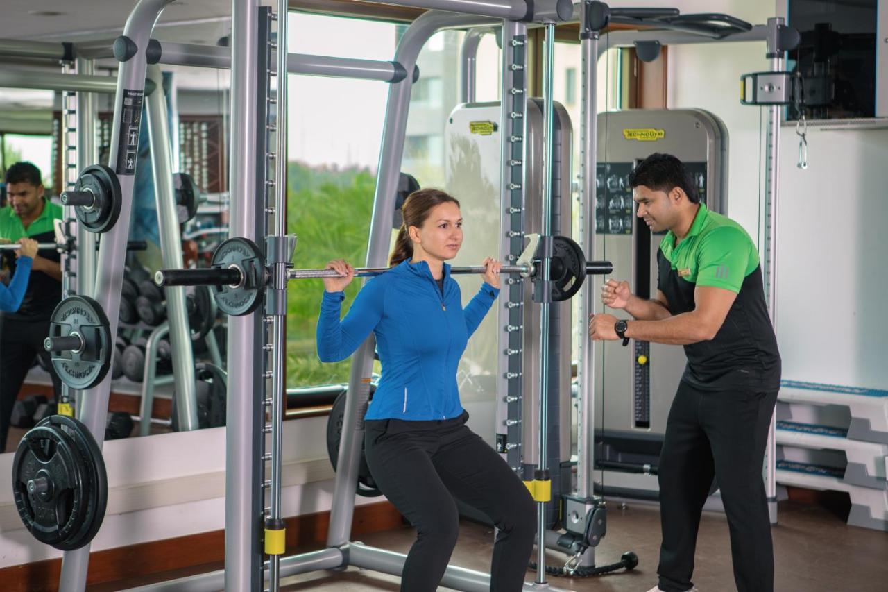 Jumeirah Messilah Beach Kuwait Kuwait City Esterno foto A personal trainer assisting a woman with a squat